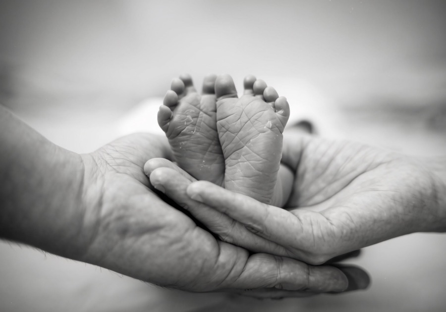 Tiny newborn feet held safely in caring hands